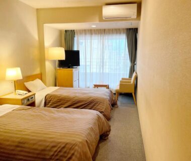 Twin beds with bedside lamps, TV and balcony in Hotel Kimiyoshi room, Yamanashi, Chūbu