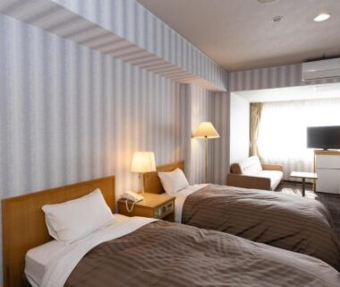 Twin beds with bedside lamps and seating area at Hotel Kimiyoshi in Yamanashi, Chubu