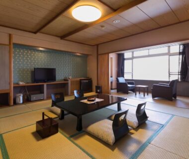Tatami-floored room with low table and zaisu chairs at Hotel Kimura in Gunma