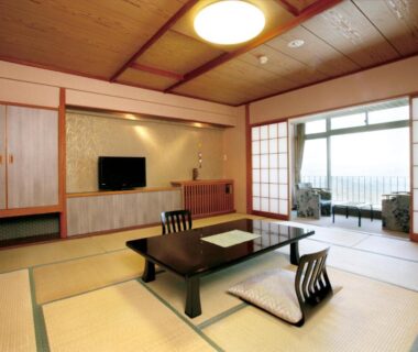 Tatami room with low table, floor chairs, shoji screens and balcony at Hotel Kimura in Gunma