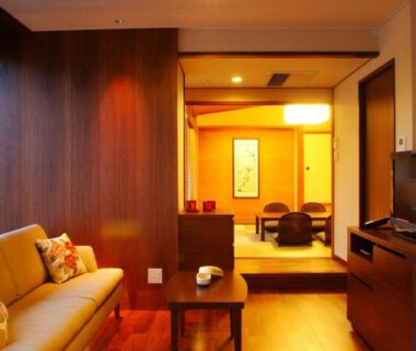 Tatami seating area with sofa, low table and shoji screens at Hotel Kinparo in Hyōgo, Kansai