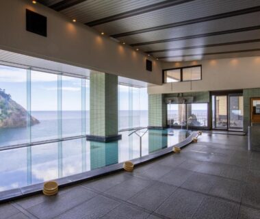 Spacious indoor bath with tiled floor, low stools, sea view and rocky islet, Hotel Kinparo, Hyōgo
