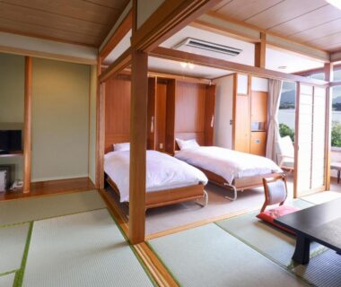 Tatami room with twin beds, low table and balcony with mountain view at Hotel Koryu Yamanashi