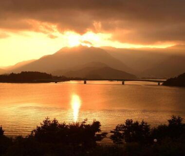 Sunset over a lake with mountains and bridge near Hotel Koryu in Yamanashi, Chūbu