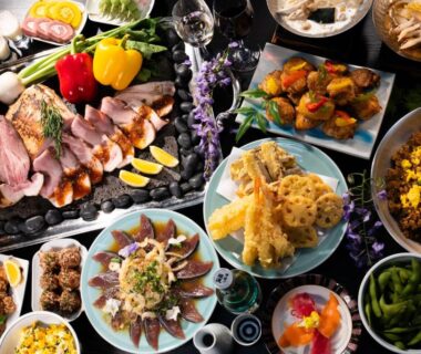 Selection of tempura, sliced fish, grilled meats, rice and small side dishes on a low dining table