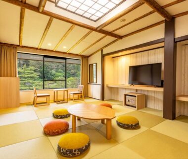 Bright tatami room with low round table, floor cushions and garden view at Hotel Koyokan in Iwate, Tōhoku