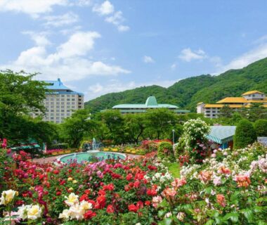 Rose garden with fountain and hotel buildings set against green mountains at Hotel Koyokan in Iwate
