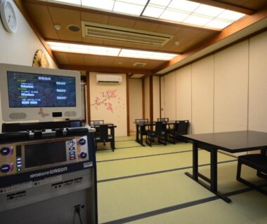 Tatami room with karaoke machine, low tables and chairs at Hotel Manyotei in Tochigi, Kanto region