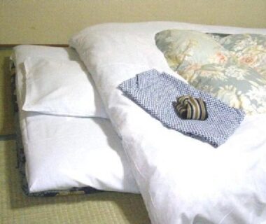 Futon bedding on tatami mat with folded robe and small wrapped item