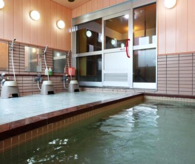 Tiled indoor onsen bath with stools and handheld showers at Hotel Meribel Tsugaike, Nagano