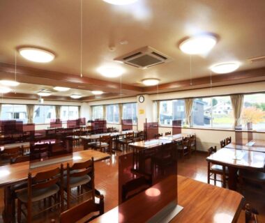 Communal dining room with wooden tables and clear dividers at Hotel Meribel Tsugaike, Nagano, Chūbu, Japan