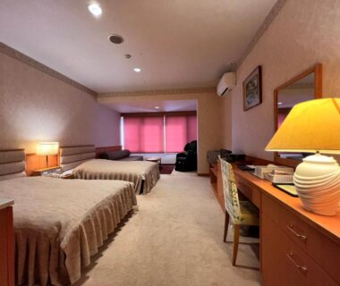 Three single beds in carpeted guest room with desk, lamps and curtained window at Hotel Miki, Gifu