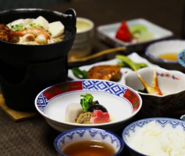 Assorted small ceramic dishes with rice, soup and simmering pot on a low lacquered table