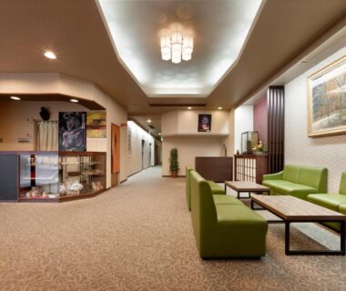 Lobby with green sofas, low tables, reception counter and corridor at Hotel Mimatsu in Nara