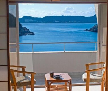 Shoji screens opening to balcony with chairs and ocean view at Hotel Nagisaya, Wakayama