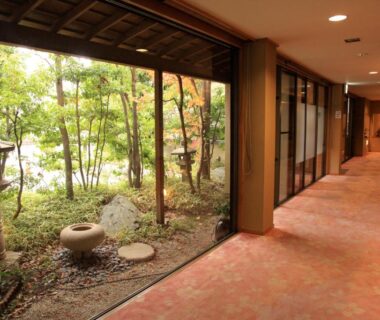 Carpeted corridor beside a stone lantern garden at Hotel New Kotobuki, Nagano, Chūbu, Japan
