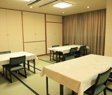 Tatami-floor dining space with tables and chairs, sliding panels and curtains at Hotel New Kotobuki Nagano