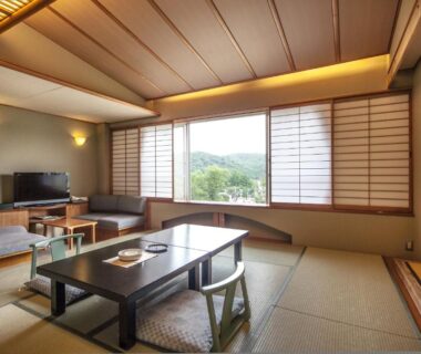 Traditional tatami room with low table, shoji screens, seating area and greenery view at Hotel New Mitoya Miyagi