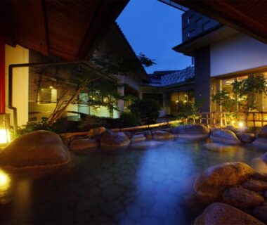 Evening rock-lined open-air bath with lanterns at Hotel New Mitoya in Miyagi Tōhoku