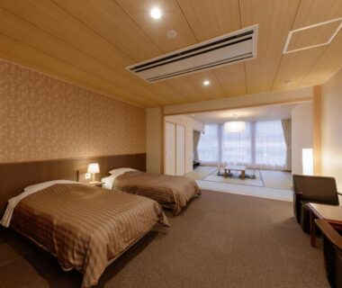 Twin beds, tatami seating area and low table in Hotel New Momiji Tochigi