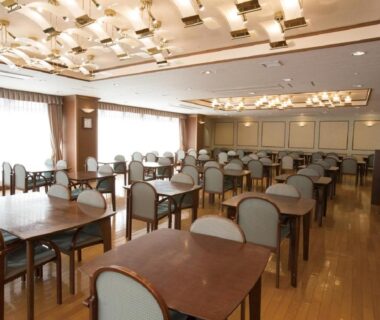 Large ryokan dining room with wooden tables and upholstered chairs at Hotel New Momiji in Tochigi