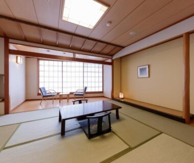 Tatami room with low table, shoji screens and seating by window at Hotel New Momiji in Tochigi, Kantō