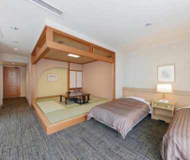 Raised tatami seating area with low table, shoji screens and twin beds at Hotel New Momiji in Tochigi, Kantō Japan