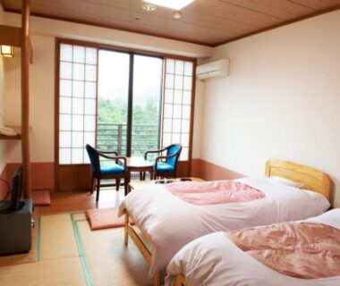 Twin beds on tatami with shoji doors and seating area at Hotel New Ohruri in Tochigi
