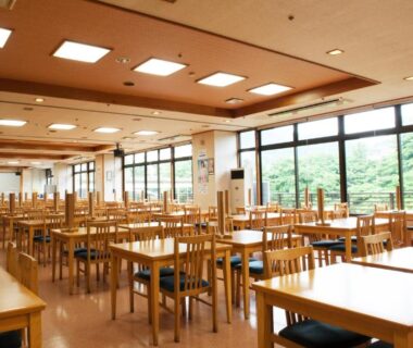 Spacious ryokan dining hall with wooden tables and large windows overlooking greenery, Hotel New Ohruri, Tochigi