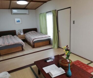 Tatami room with twin beds, low wooden table and cushions at Hotel New Otani in Chiba