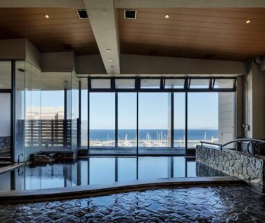 Indoor onsen bath with floor-to-ceiling windows overlooking the sea at Hotel New Tsuruta in Oita, Kyushu