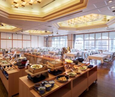 Spacious ryokan dining hall with buffet stations and large windows at Hotel New Tsuruta in Ōita