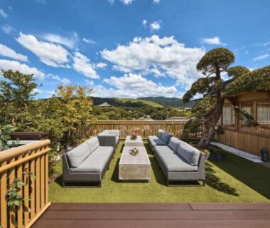 Outdoor rooftop terrace with cushioned sofas at Hotel New Wakasa, distant Nara hills and blue sky
