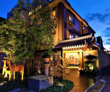 Evening exterior of Hotel New Wakasa with lit entrance, lantern, garden path and decorative deer sculptures in Nara, Kansai, Japan