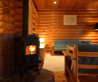 Warm wood-paneled lounge with wood-burning stove and seating at Hotel Nidom, Hokkaidō, Japan