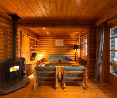Rustic wooden lounge with wood burning stove and seating at Hotel Nidom in Hokkaidō