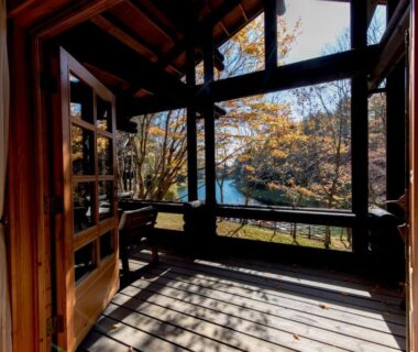 Wooden veranda overlooking lake and autumn trees at Hotel Nidom in Hokkaidō