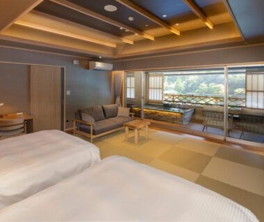Spacious tatami room with twin beds, low table, sofa and large garden view window at Hotel Okada Kanagawa