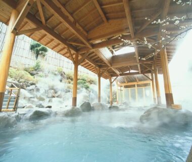 Steaming rock-lined onsen bath at Hotel Okada in Kanagawa prefecture with covered wooden roof and bamboo screens