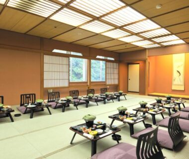 Large tatami banquet room with low dining tables, cushions, shoji windows and a tokonoma alcove