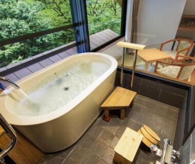 In-room soaking tub with garden view, wooden stools and floor-level washing area at Hotel Okuyumoto Kanagawa