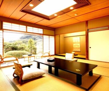 Tatami room with low table, zabuton cushions, shoji screens and garden view at Hotel Okuyumoto in Kanagawa