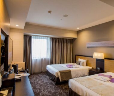 Twin bedroom with two beds, bedside lamp, TV and window at Hotel Ole in Shizuoka