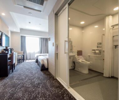 Spacious accessible twin room with open bathroom, grab bars, desk, TV and window at Hotel Ole Shizuoka