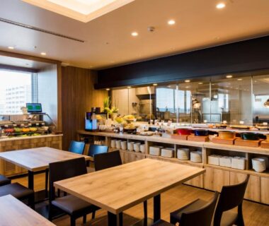 Modern dining room with buffet counter, wooden tables and city view through large windows