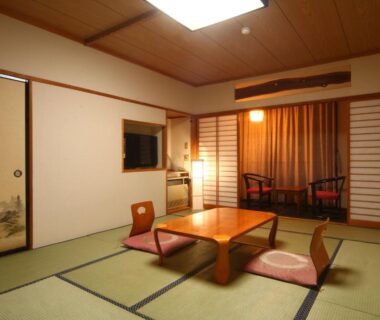 Tatami room with low table, zabuton chairs and shoji screens at Hotel Omodaka in Nagano, Chubu