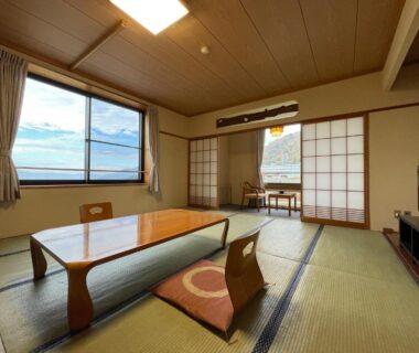Spacious tatami room with low table, shoji screens and window overlooking mountains in Nagano