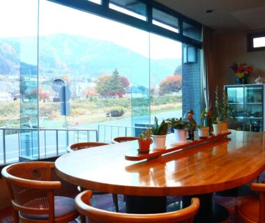 Wooden dining table by large window at Hotel Omodaka with mountain view in Nagano
