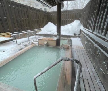 Wooden outdoor onsen bath with milky water and snow banks, Hotel & Onsen 2307 Shigakogen Nagano