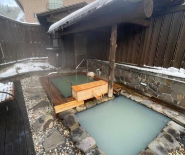 Wooden and stone onsen baths with milky water at Hotel & Onsen 2307 Shigakogen in Nagano